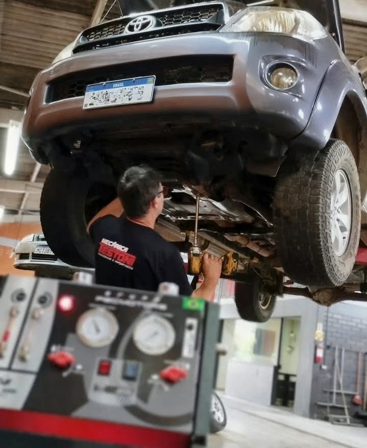 Mecânico trabalhando sob uma caminhonete Toyota no elevador